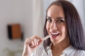 Good-looking brunette puts a chewing gum into her mouth looking into the camera Royalty Free Stock Photo