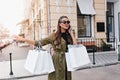 Good-looking brunette woman catches taxi after shopping. Outdoor portrait of beautiful long-haired lady talking on phone Royalty Free Stock Photo