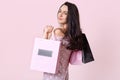 Good looking brunette woman stands sideways, holds shopping bags, looks directly at camera, returns from shopping mall in good Royalty Free Stock Photo