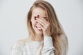 Good-looking emotional young Caucasian woman with blonde long hair, closing eyes with hand while laughing out loud Royalty Free Stock Photo