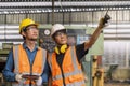 Good looking engineer in uniform and helmet using tablet computer at factory. Worker with safety helmet checking quality in Royalty Free Stock Photo