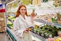 Good-looking female is choosing fresh vegetables and fruits in the store Royalty Free Stock Photo