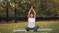 Good-looking girl is putting hands in namaste sitting in lotus position and breating relaxing her body and mind