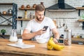 Good looking handsome bearded man is sitting in the kitchen having breakfast cereals and milk, coffee and bananas. reading morning Royalty Free Stock Photo