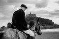 Good Looking Male Horse Rider riding horse on beach in traditional riding clothing with St Michael`s Mount in background