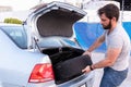 young man taking the spare tire out of the trunk of a car, on the road having an emergency Royalty Free Stock Photo