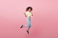 Good-looking mulatto lady expressing positive emotions during photoshoot. Glad trendy girl in jeans and sneakers jumping Royalty Free Stock Photo
