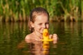 Good looking positive child swimming in local lake alone, holding her rubber duck for water, enjoying summer holidays, swimming Royalty Free Stock Photo