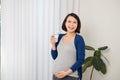 Good looking pregnant woman holding a glass of water while standing near window Royalty Free Stock Photo