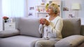 Good-looking senior lady holding tea cup, sitting on home sofa, enjoying weekend Royalty Free Stock Photo