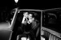 Good looking couple, handsome man in suit, beatiful woman in red dress, embrace passionately in vintage car Royalty Free Stock Photo