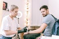 Good-looking tattoo master with boyish haircut wiping off area of bare skin