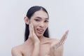 A good-looking transwoman freshens up by washing her face with hydrating and moisturizing facial wash. Studio shot isolated on a Royalty Free Stock Photo