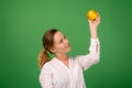 A good-looking woman of forty in a white shirt on a green background smiles and holds a fresh apple in her hands. Healthy eating, Royalty Free Stock Photo