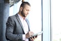 Good looking young businessman in casual clothes reading his note pad while standing in the office