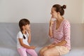 Good looking young European language therapist teaching small female child right sounds pronunciation, working on speech