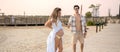 Good looking young fit man with open shirt and muscular body with abs holding hands with his pregnant wife at the beach. Royalty Free Stock Photo