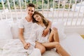 Good-looking young man embracing his lovely long-haired wife and lazy resting in bed in saturday morning. Portrait of