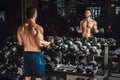 Good looking young man lifting dumbbells and working on his biceps in front of the mirror at the gym Royalty Free Stock Photo