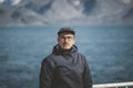 Good looking young man looking forward and smiling while standing on the deck of a ship in the Arctic. On Board Sarfaq Royalty Free Stock Photo
