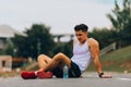 Exhausted young man in sleeveless taking rest after long run in park Royalty Free Stock Photo