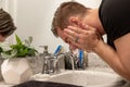 Good Looking Young Man Washing Hands and Face in Home Bathroom Mirror and Sink Getting Clean and Groomed During Morning Routine Royalty Free Stock Photo