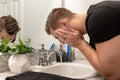 Good Looking Young Man Washing Hands and Face in Home Bathroom Mirror and Sink Getting Clean and Groomed During Morning Routine Royalty Free Stock Photo