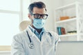 Good looking young man in white lab coat and protective mask Royalty Free Stock Photo