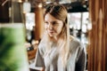 A good looking youthful slim girls,wearing casual style, is standing next to the coffee machine and smiling in a cozy