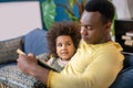 Little darkskinned girl looking at dad with book