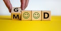Good mood symbol. Male hand flips a wooden cube and changes the word `good` to `mood`. Positive smiles. Beautiful yellow table