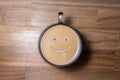 Good morning coffee smile cup on wooden background. Cup of delicious hot coffee with foam and smile on color background