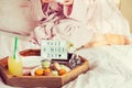 Good morning concept. Breakfast in bed with Have a nice day text on lighted box, juice and macaroons on tray and blurred woman in