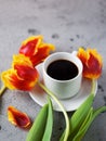 Good morning a Cup of hot espresso coffee, Tulip flowers on a stone gray table