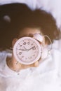 Good morning. Happy woman in bed waking up and holding up an alarm clock. Waking up at 7 a.m. early morning. Shiny and sunny Royalty Free Stock Photo