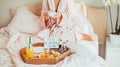 Good morning mood. Young woman in bathrobe sitting on the bed, drinking coffee and has her breakfast in bed with Have a nice day Royalty Free Stock Photo