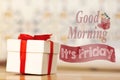 Good morning it`s friday message with white gift box with red ribbon on wood background Royalty Free Stock Photo