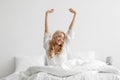 Good morning, smiling young lady waking up fully rested on white bedding, relax at home at weekend, vacation Royalty Free Stock Photo