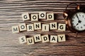 Good Morning Sunday alphabet letter with alarm clock on wooden background