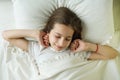 Good morning, teenage girl wakes up and smiles lying on a pillow in her bed, top view Royalty Free Stock Photo