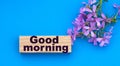 GOOD MORNING words on a wooden block on a blue background with beautiful flowers