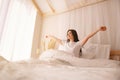Woman awakening stretching in bed in early morning