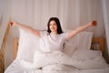 Woman awakening stretching in bed in early morning