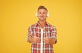 Good music is just a pair of headphones away. Happy man show thumbs ups listening to music yellow background. New Royalty Free Stock Photo