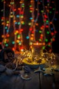 Good New Year spirit. Candle, garland, Christmas lights. Spices are anise star, an orange peel on a wooden table. Still life, cozy