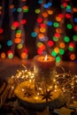 Good New Year spirit. Candle, garland, Christmas lights. Spices are anise star, an orange peel on a wooden table. Still life, cozy