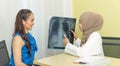 Good news. muslim female physician shows results x-ray report of the lungs to young female patient Royalty Free Stock Photo