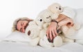 Good night. Handsome bearded male sleeping with teddy bears on in bed at home. Sleepy man in pajamas sleeping in bed Royalty Free Stock Photo