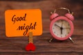 Good Night text attached with heart clip and alarm clock. Royalty Free Stock Photo