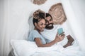 Darkskinned woman and man taking selfie in bed